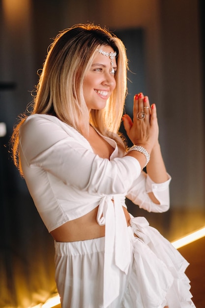 Belle fille souriante dans une robe blanche dansant dans la salle de gym