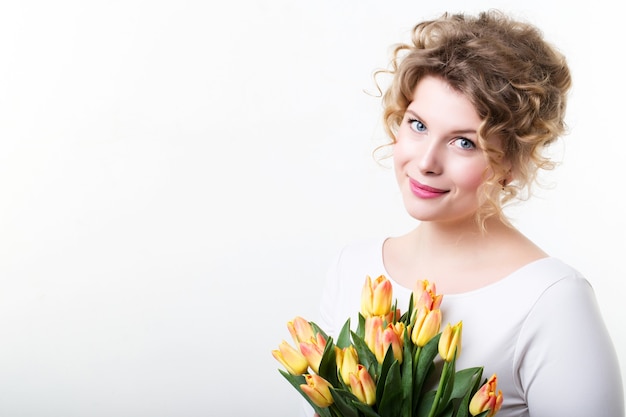 Belle fille souriante avec des fleurs sur un blanc.