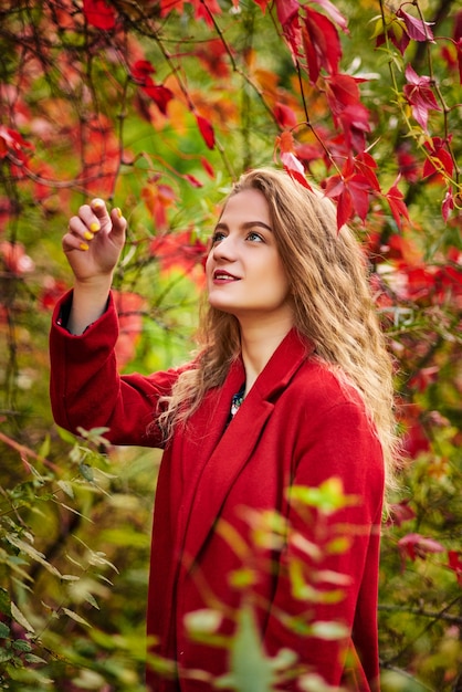 Belle fille souriante heureuse aux cheveux longs, posant dans la rue d'automne. Bouchent le portrait en plein air. Concept de mode féminine.