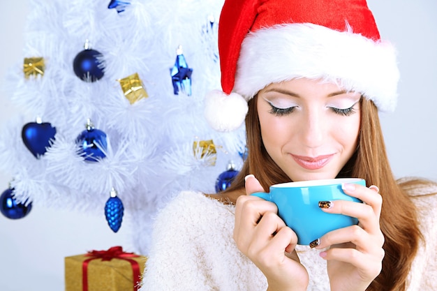 Belle fille souriante près de sapin de Noël avec tasse