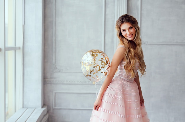 Belle fille souriante de printemps dans une robe rose avec des ballons