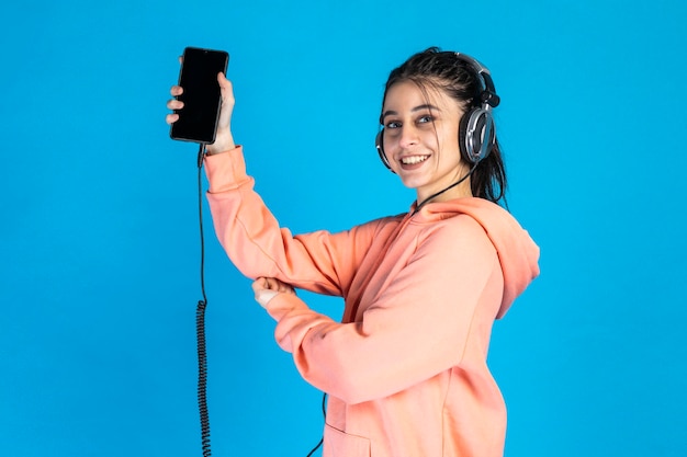 Belle fille souriante tenant son téléphone et portant un casque