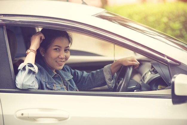 Belle fille sourit en conduisant une voiture