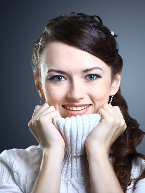 Belle fille sourit dans un pull isolé sur fond gris