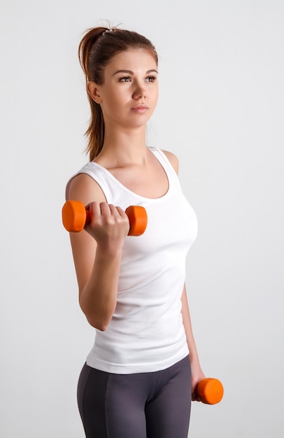 Belle fille sportive fait des exercices avec des haltères debout