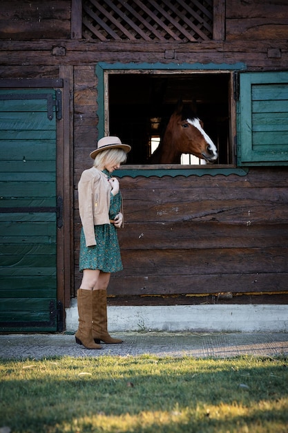 Belle fille de style bohème parle à un cheval à travers une fenêtre