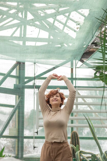 Une belle fille de taille plus appréciant debout parmi les plantes vertes