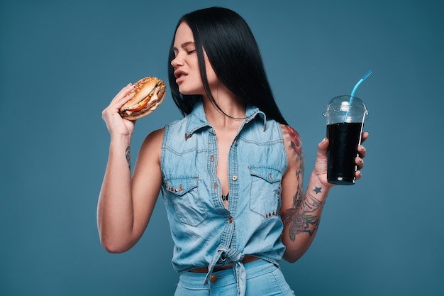 Belle fille de tatouage avec hamburger et soda