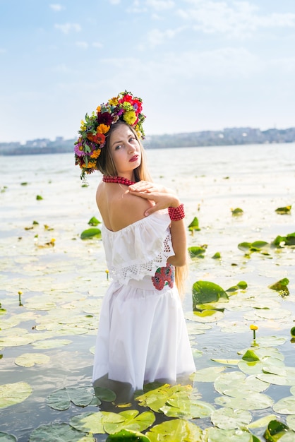 Belle fille en tenue nationale debout dans le lac