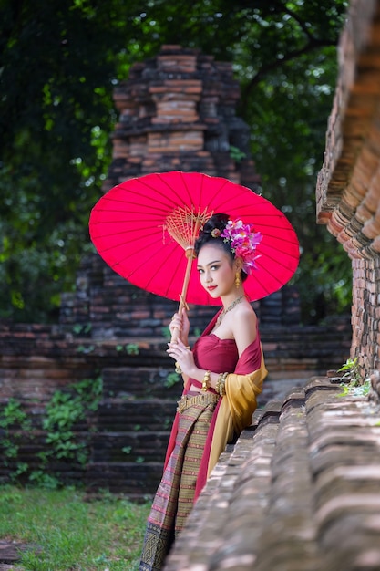 Belle fille thaïlandaise en costume traditionnel costume parapluie rouge comme temple thaïlandais