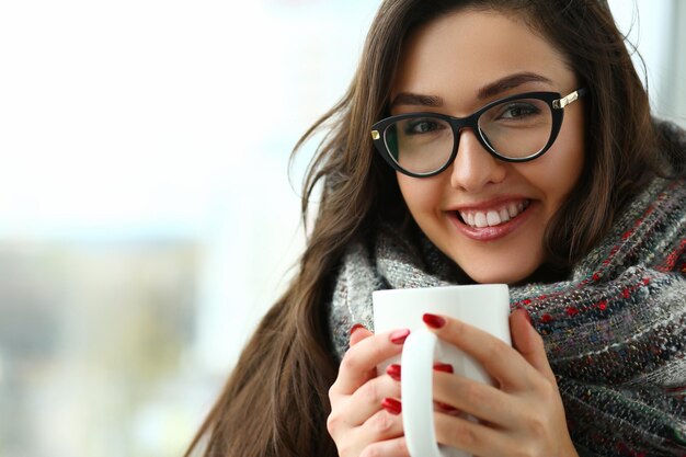 Belle fille tient une grande tasse dans les mains en gros plan