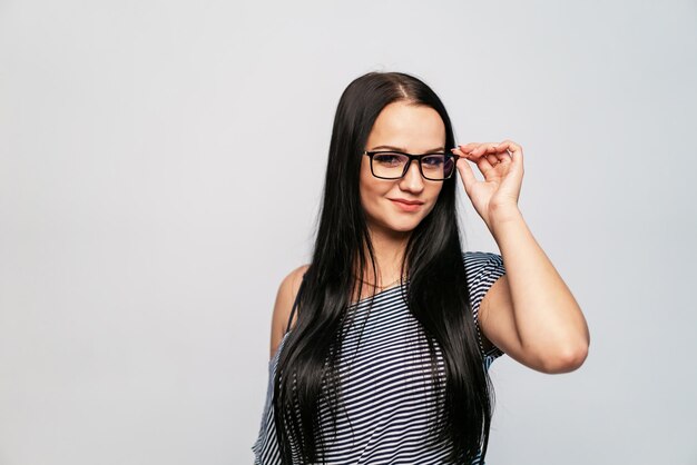 Belle fille touche une jante par des lunettes avec les doigts Femme sourit sur fond blanc isolé Gros plan