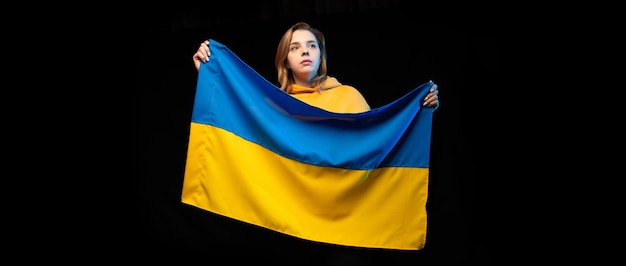 Belle fille ukrainienne avec le drapeau national de l'Ukraine sur fond noir Espace de copie Guerre ukrainienne russe Aidez et priez pour l'Ukraine Arrêtez la guerre