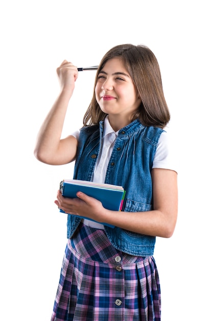 Belle fille en uniforme scolaire avec un cahier à la main sur un fond blanc