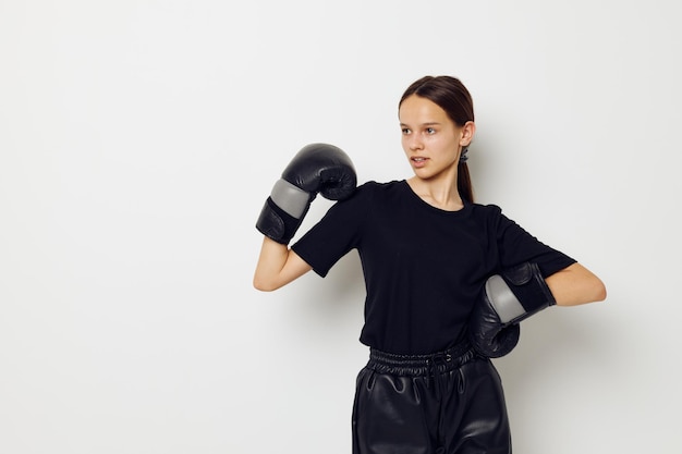 Belle fille en uniforme de sport noir gants de boxe posant Lifestyle inchangé