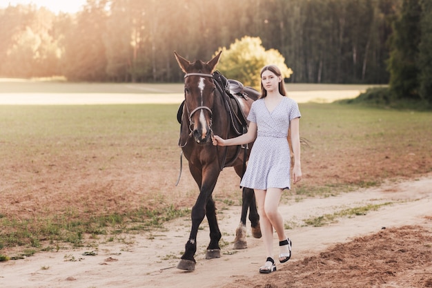 La belle fille va sur la route avec un cheval