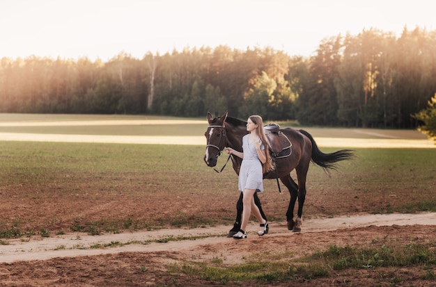 La belle fille va sur la route avec un cheval