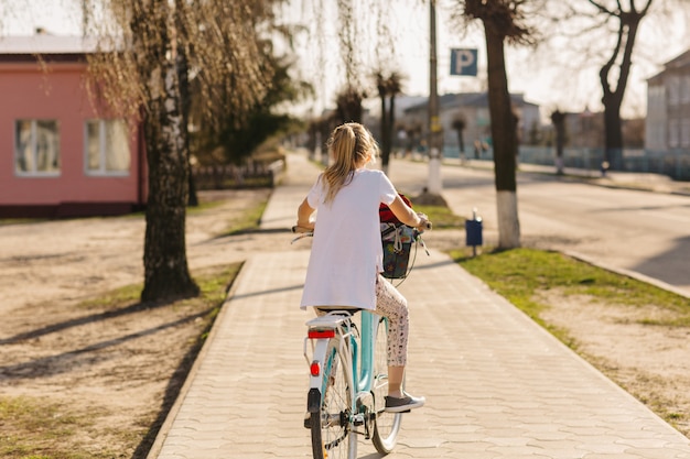 belle fille sur un vélo bleu. fille fait du vélo. vacances d'été. passer du temps avec avantage. vélo femme avec panier