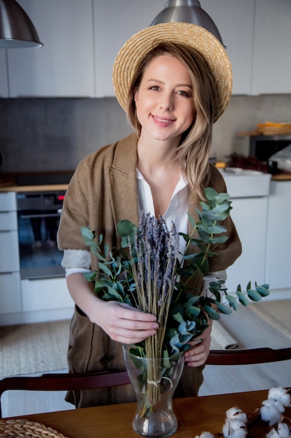 Belle fille en veste avec eucalyptus et cotonnier dans une cuisine à la maison. Concept de mode de vie sain et écologique