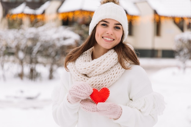 belle fille en vêtements d&#39;hiver blanc dans la rue qui détient le cœur à la Saint-Valentin