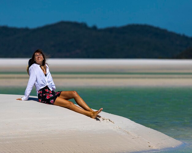 une belle fille vêtue d'une robe, d'une chemise et d'un chapeau se promène sur la plage de whitehaven, whitsundays