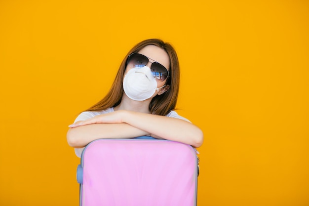 Belle fille vêtue d'une robe d'été blanche avec une valise Masque médical sur le visage Frontières fermées