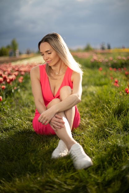 Belle fille vêtue d'une robe rose dans un parc avec des tulipes