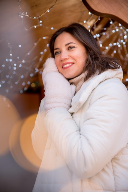 Belle fille vêtue d'une veste blanche et d'un chapeau blanc la fille sourit tasse de café à la main maison d'été en bois fille se réjouit des émotions