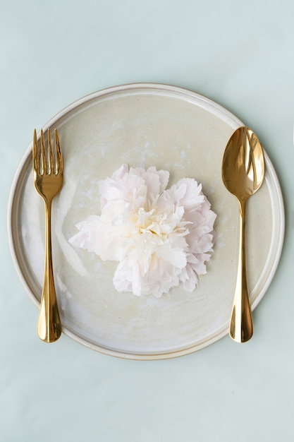 Belle fleur sur une assiette avec cuillère et fourchette dorées