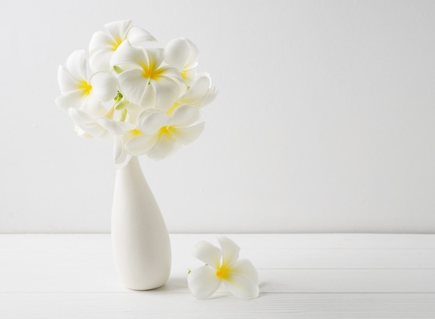 Belle fleur spa Frangipani dans un vase blanc en céramique moderne sur la surface du mur blanc de table en bois avec espace copie