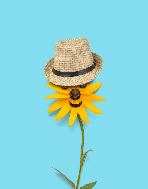 Photo une belle fleur avec des yeux et un chapeau sur fond bleu.