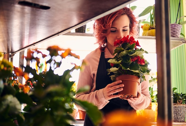 Belle fleuriste rousse en uniforme travaillant dans un magasin de fleurs.