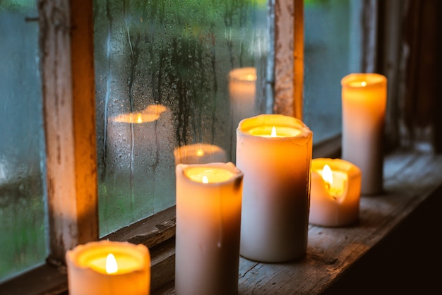 Belle avec des gouttes de pluie sur la fenêtre et des bougies allumées.