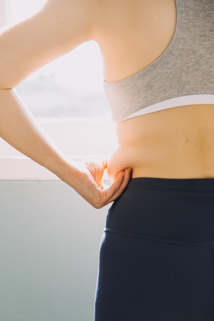 Belle grosse femme avec ruban à mesurer Elle utilise sa main pour presser l'excès de graisse isolé sur fond blanc Elle veut perdre du poids le concept de chirurgie et décomposer la graisse sous le