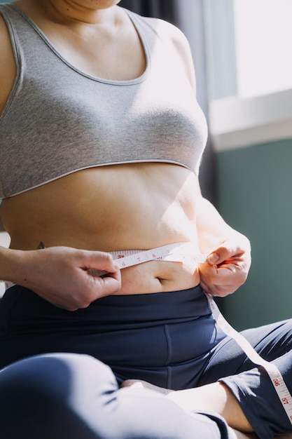 Belle grosse femme avec ruban à mesurer Elle utilise sa main pour presser l'excès de graisse isolé sur fond blanc Elle veut perdre du poids le concept de chirurgie et décomposer la graisse sous le