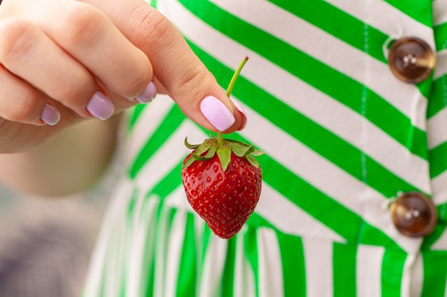 Belle grosse fraise rouge dans une main. Fermer.