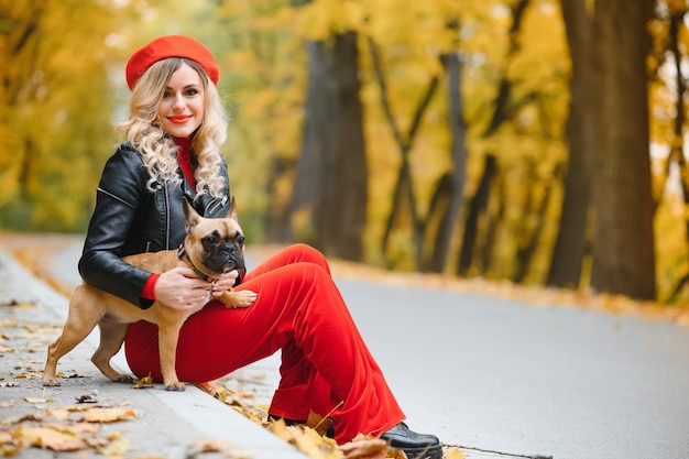 Belle et heureuse femme appréciant la promenade dans le parc avec son adorable bouledogue français