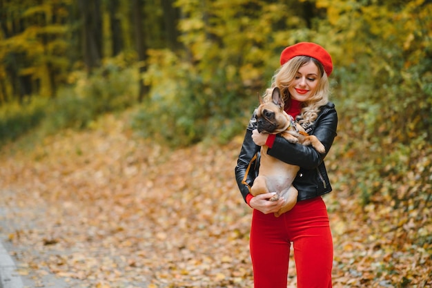 Belle et heureuse femme appréciant la promenade dans le parc avec son adorable bouledogue français