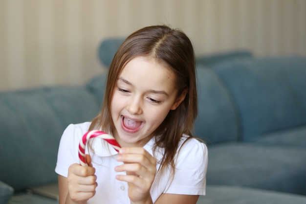 Belle heureuse petite fille souriante tenant une canne de Noël