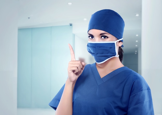 Belle infirmière asiatique avec masque médical pointant sa main