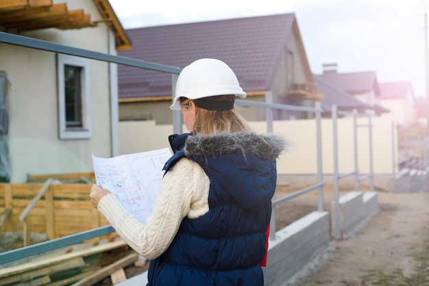 Une belle ingénieure se tient sérieuse devant un chantier de construction