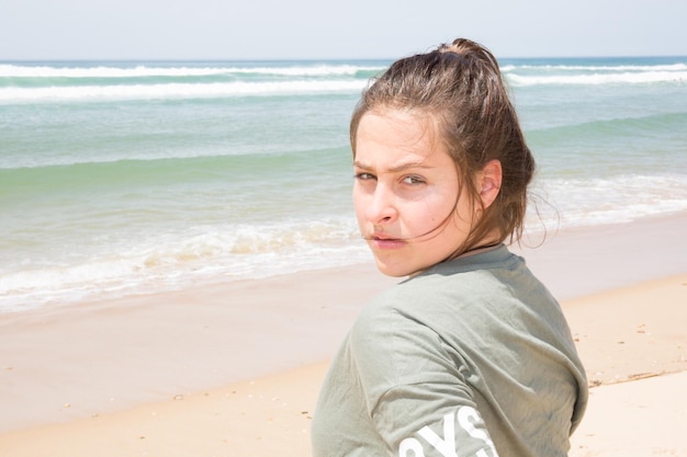 belle jeune adolescente debout sur la plage, avec le rivage en arrière-plan