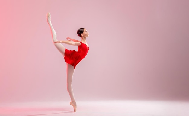 Belle jeune ballerine sur fond blanc La ballerine est vêtue d'un justaucorps rouge justaucorps rose chaussons de pointe