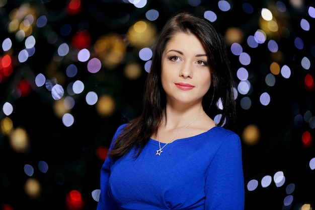 Belle jeune belle jeune femme en robe de soirée élégante bleue avec des lumières de Noël bokeh