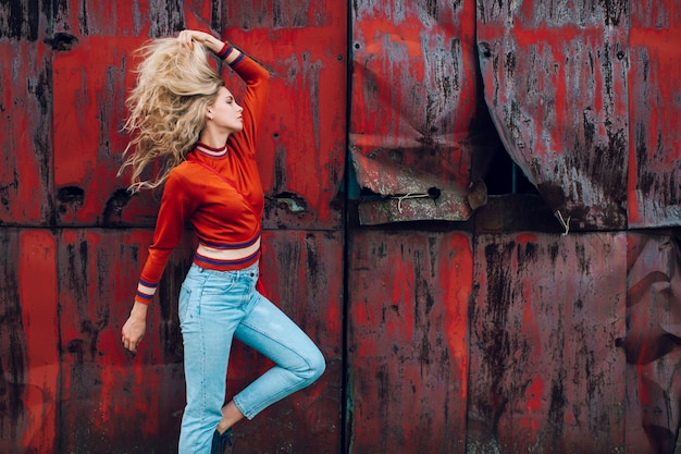 Photo belle jeune blonde posant sur un mur métallique