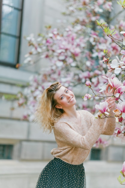 Belle jeune blonde près d'un Magnolia en fleurs