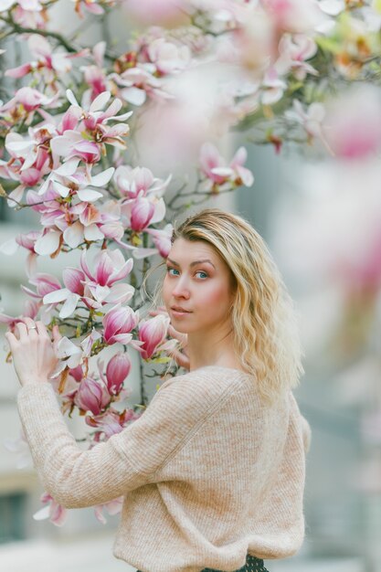 Belle jeune blonde près d'un Magnolia en fleurs