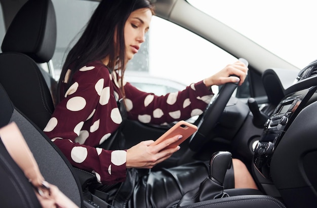 Belle jeune brune à l'intérieur d'une voiture d'équitation automobile moderne