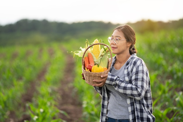 Belle jeune brune Portrait Famer Woman hand holding Vegetables in the bamboo basket on green