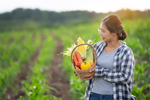 Belle jeune brune Portrait Famer Woman hand holding Vegetables in the bamboo basket on green